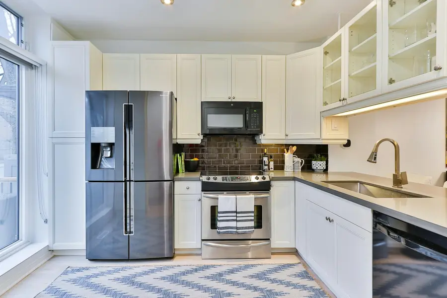 Silver French door refrigerator beside white kitchen cabinets