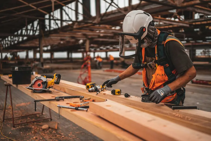 Contractor cutting a board with a power tool on a job site