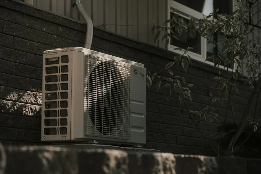 Outdoor air conditioning condenser against a brick wall